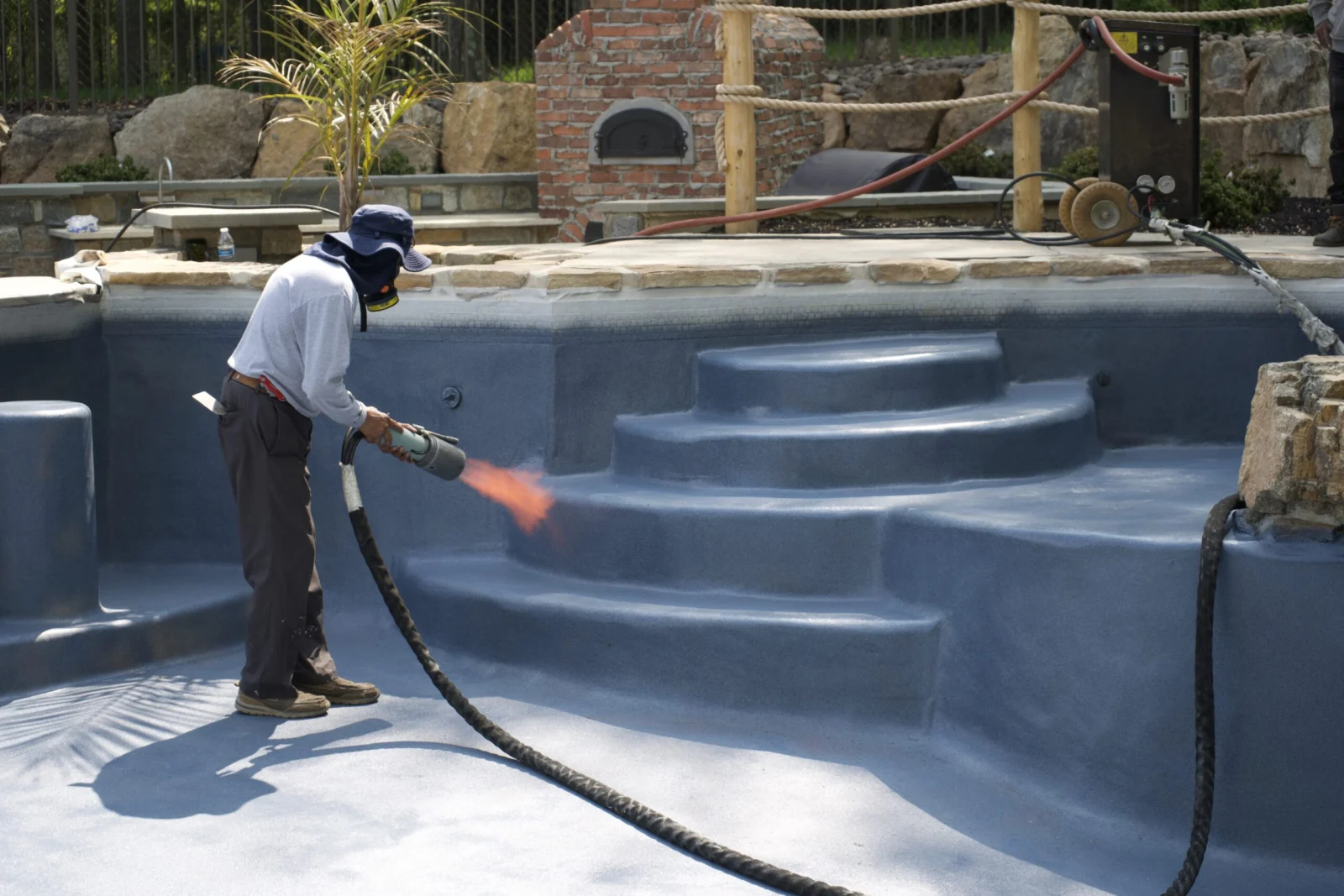 ecoFINISH aquaBRIGHT being flame-sprayed onto a pool interior by a trained applicator